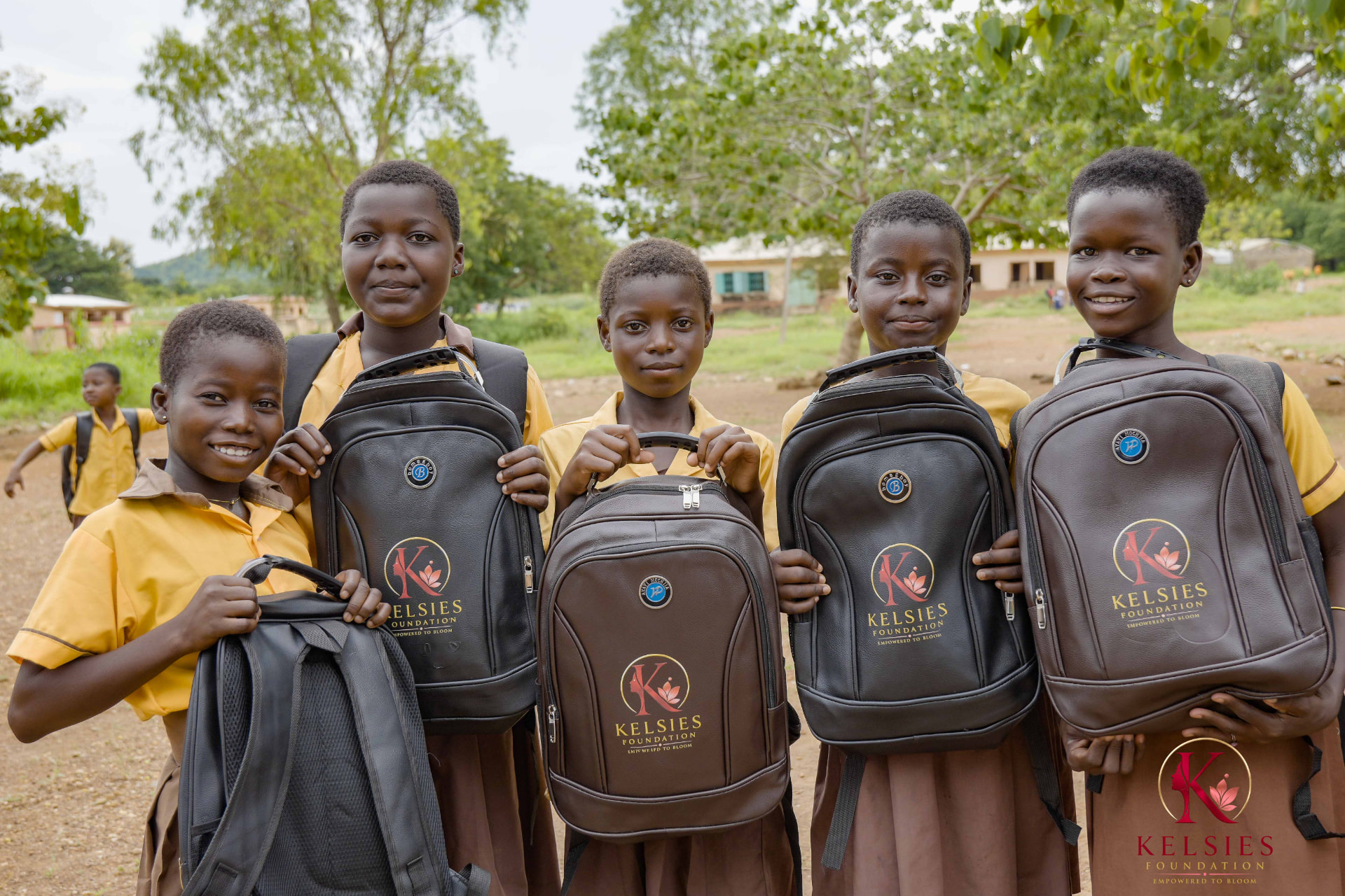 Five smiling schoolgirls displaying their Kelsies Foundation backpacks