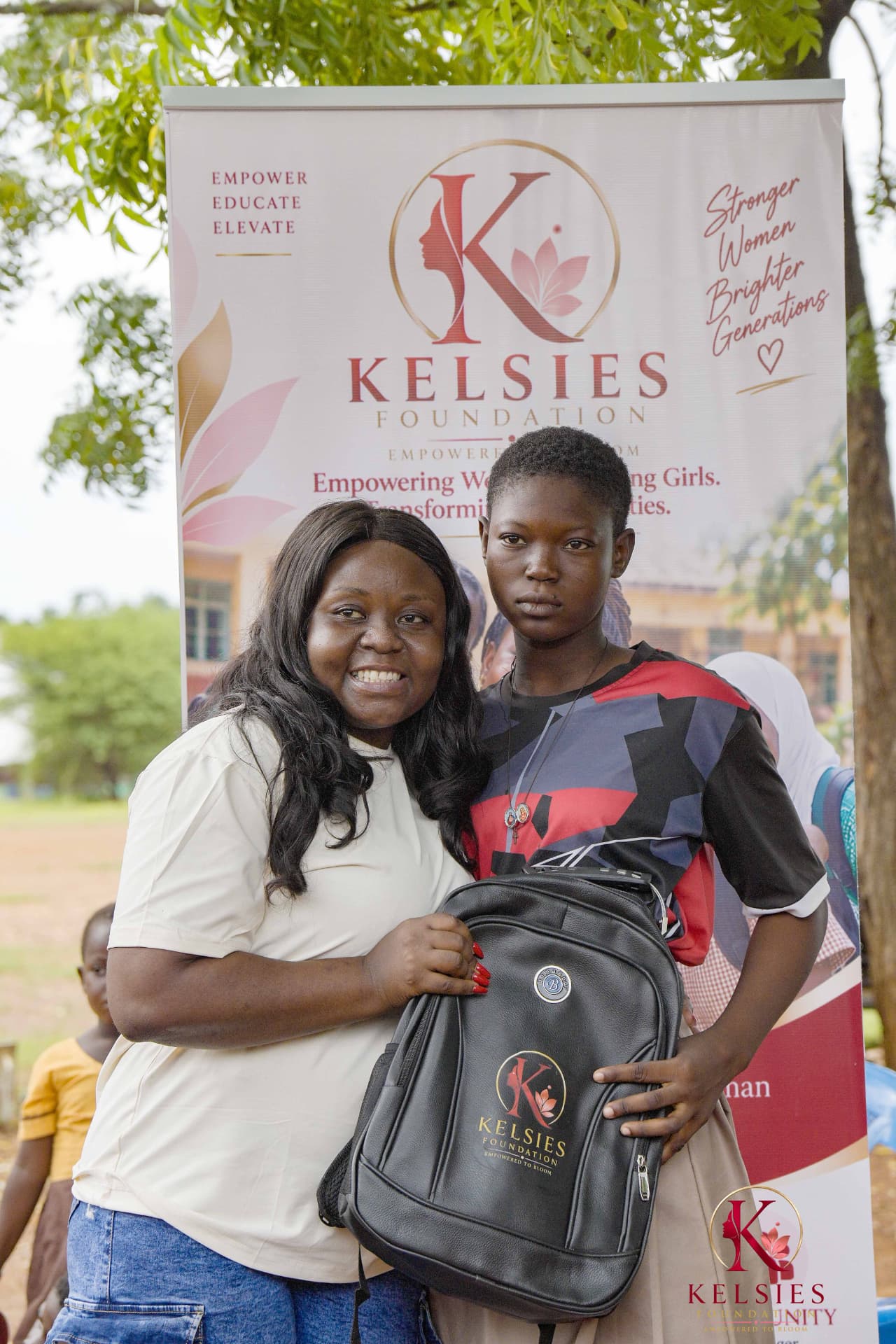 A Kelsies Foundation representative presenting a backpack to a student