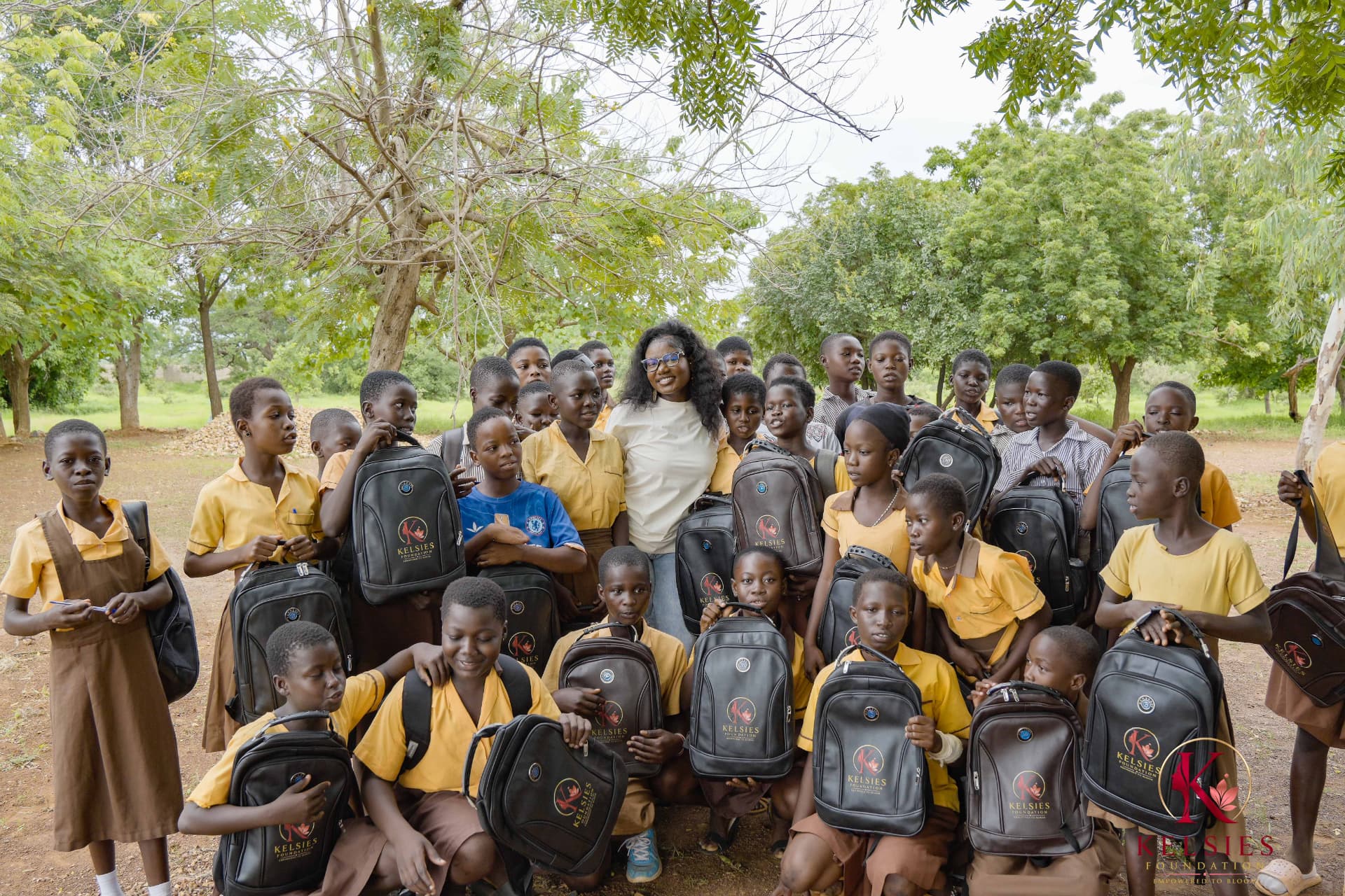 Students gathered beneath trees with their new school backpacks